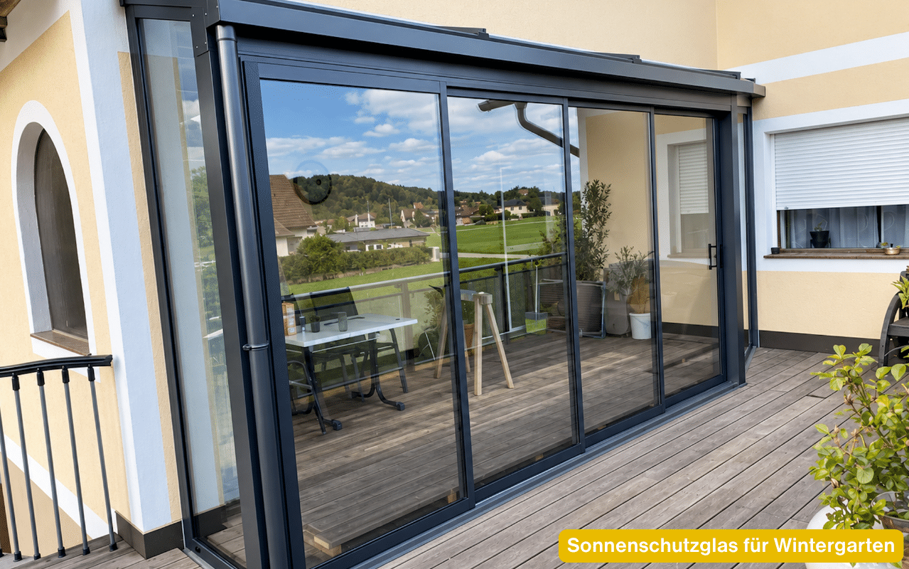 Sonnenschutzglas für Wintergarten – große Glas-Schiebeelemente mit dunklen Rahmen an einer verglasten Terrasse