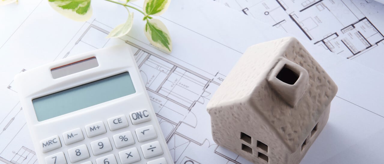 Statik-Berechnung - Plan für Terrassenüberdachung zeigt Bauplan mit Modellhaus und Taschenrechner für Planung durch Statiker und Fachmann.