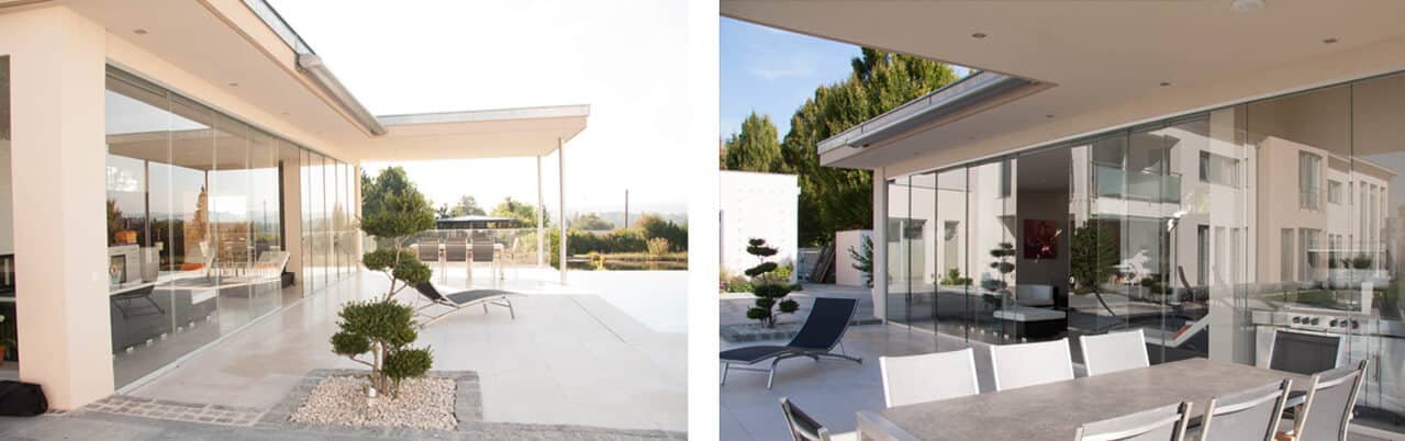 Moderne Villa mit großer Terrasse und transparenten Glasschiebetüren. Innen- und Außenbereich gehen fließend ineinander über, mit Sitzmöbeln, Pflanzen und klarer Architektur.