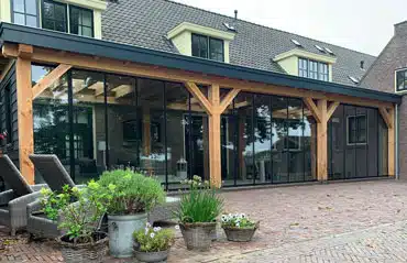 Verglaste Holzterrasse mit Glasfront. Sunflex Schiebe-Dreh-Systeme zum Falten SF35 schließen den Freisitz.