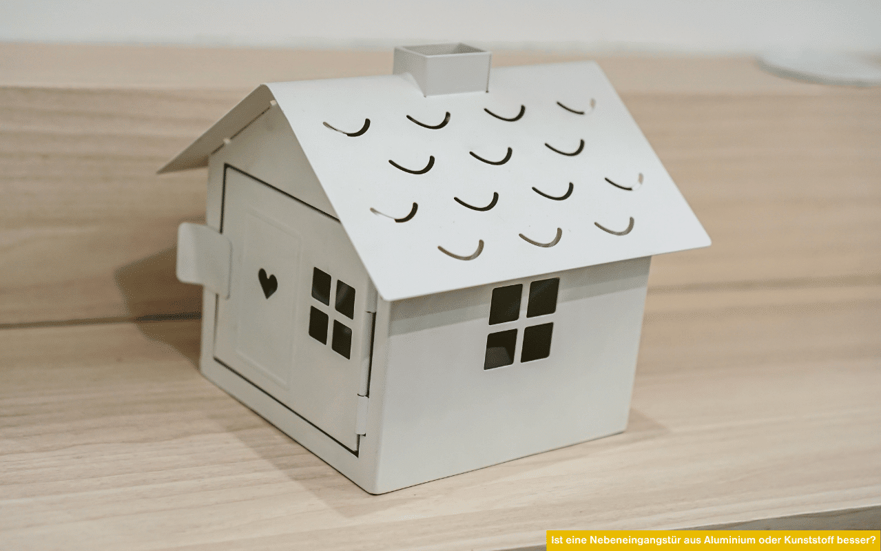 Symbolisches Miniaturhaus aus Blech auf Holzfläche - ist eine Nebeneingangstür aus Aluminium oder Kunststoff besser für Ihr Zuhause?