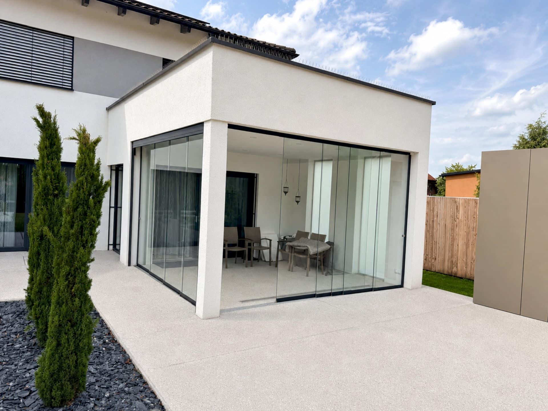 Terrassenverglasung mit Ganzglas-Schiebetüren unter dem Flachdach-Vorbau