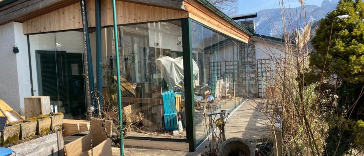 Moderne Pergola mit Glasschiebewänden im Salzkammergut schützt vor Wind und Wetter.