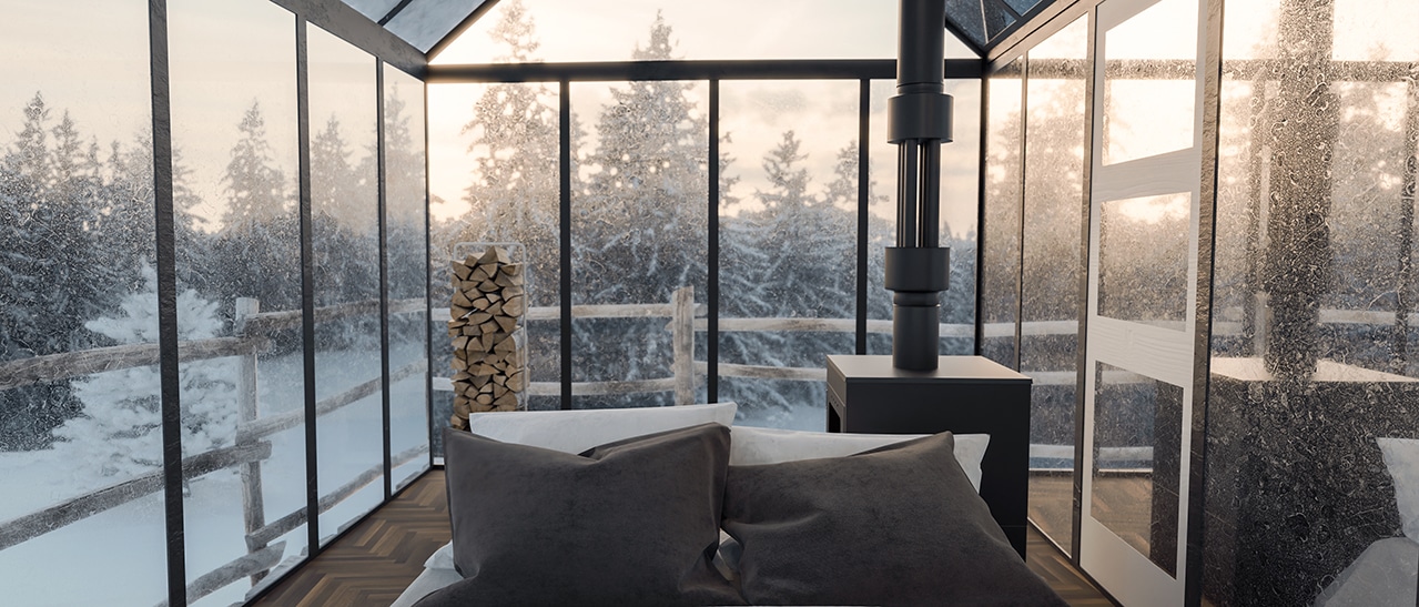 Ein moderner Wintergarten mit Glasdach im verschneiten Wald. Ein Kaminofen spendet Wärme, ein Sofa lädt zum Entspannen ein.