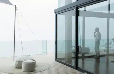 Moderner Wohnraum mit Glasfront zeigt elegante Hebeschiebetüren mit optimalem U-Wert für energieeffizientes Wohnen und viel Tageslicht