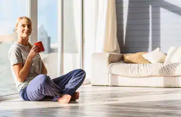 Frau sitzt 2023 entspannt vor neuen Fenstern und freut sich über attraktive Preise.