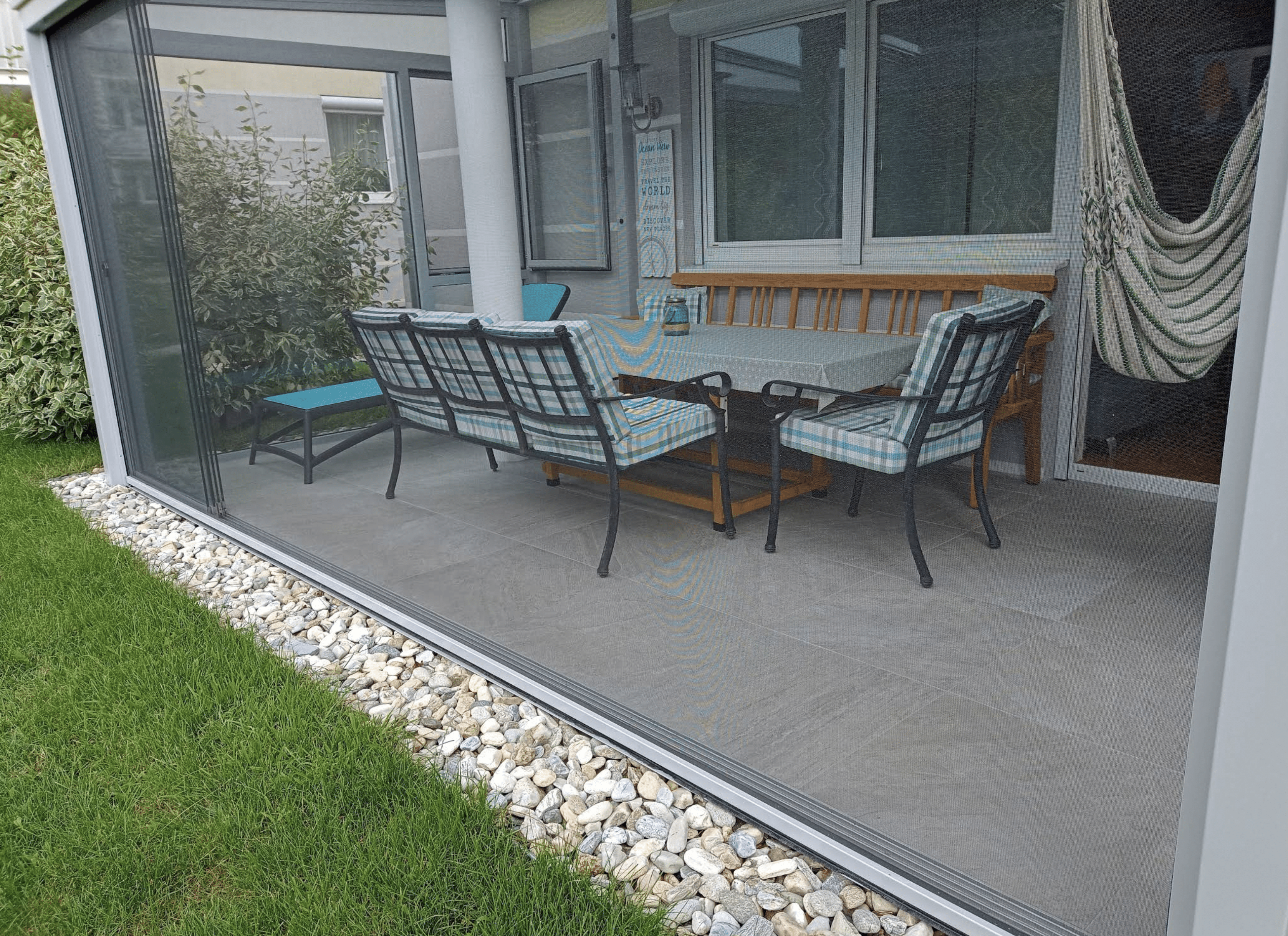 Verglaste Terrasse mit weit geöffneten Schiebeelementen vom Garten aus mit geschlossener Verschattung