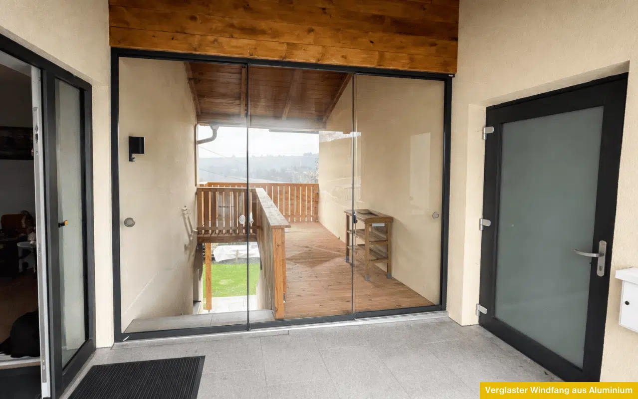 Verglaster Windfang mit Glasschiebetüren im Eingangsbereich, schlanke Profile und viel Licht.