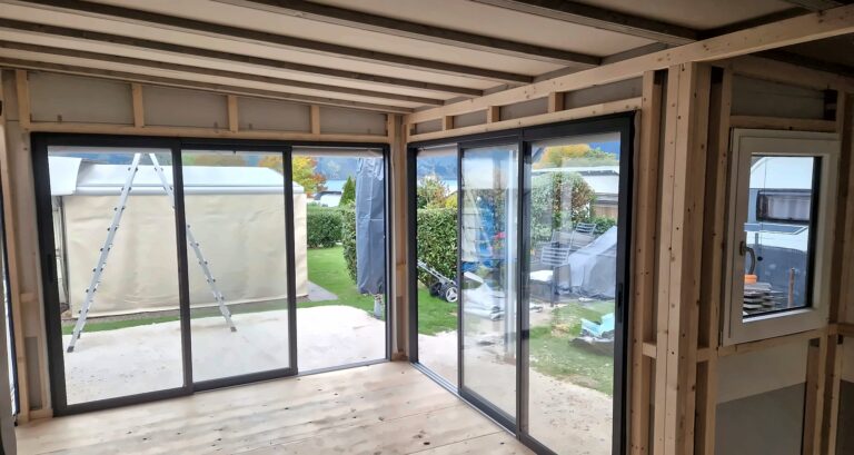 Blick aus dem Vorbau durch die Schiebeelemente über Eck in den Garten, vor dem Innenausbau