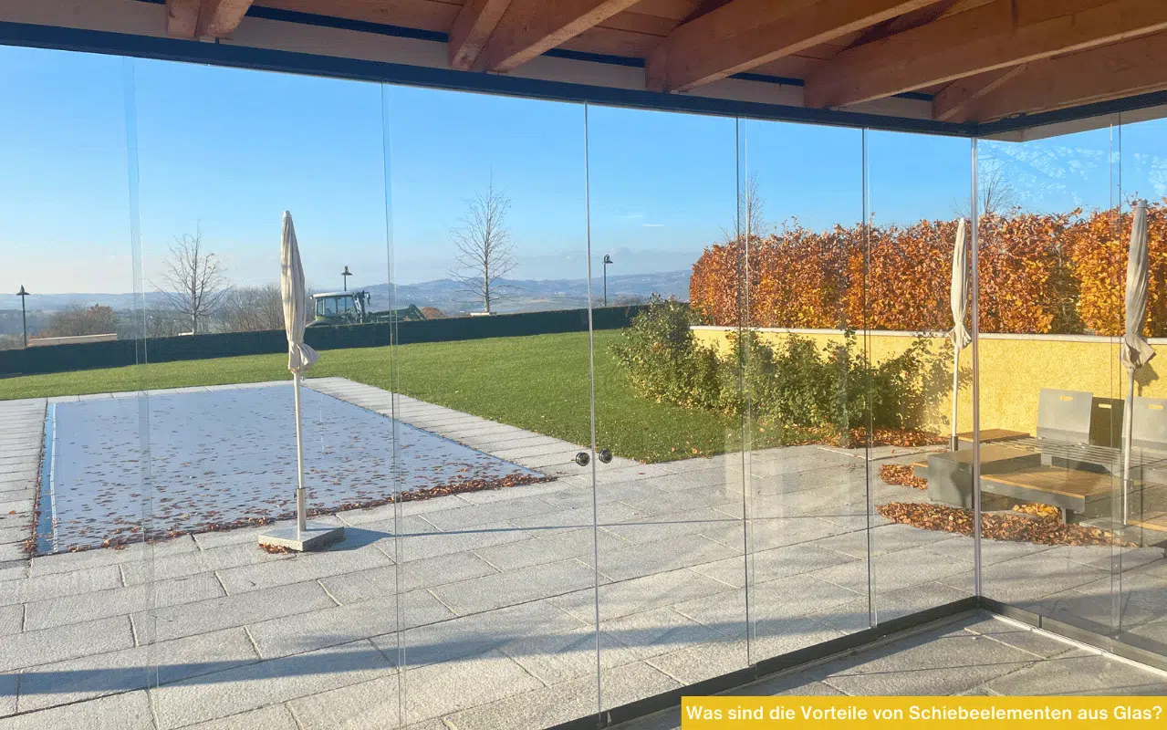 Rahmenlose Glasschiebewände bieten einen freien Blick von einer überdachten Terrasse auf einen Pool und eine Hügellandschaft.