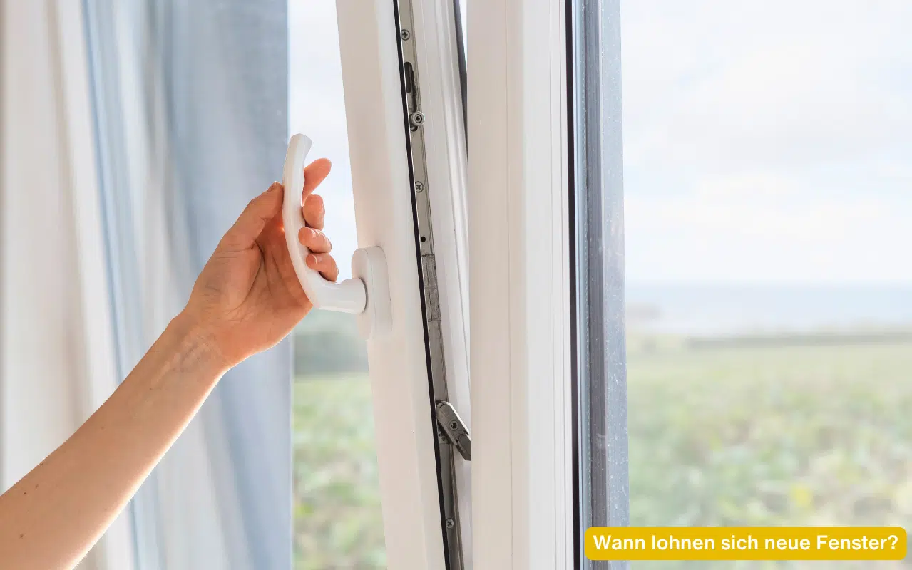 Wann lohnen sich neue Fenster – modernes weißes Fenster wird geöffnet mit weitem Ausblick ins Grüne