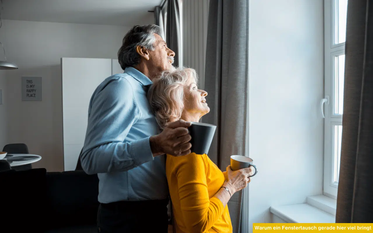Warum ein Fenstertausch gerade hier viel bringt Paar blickt entspannt aus dem Fenster und genießt Ruhe und Tageslicht