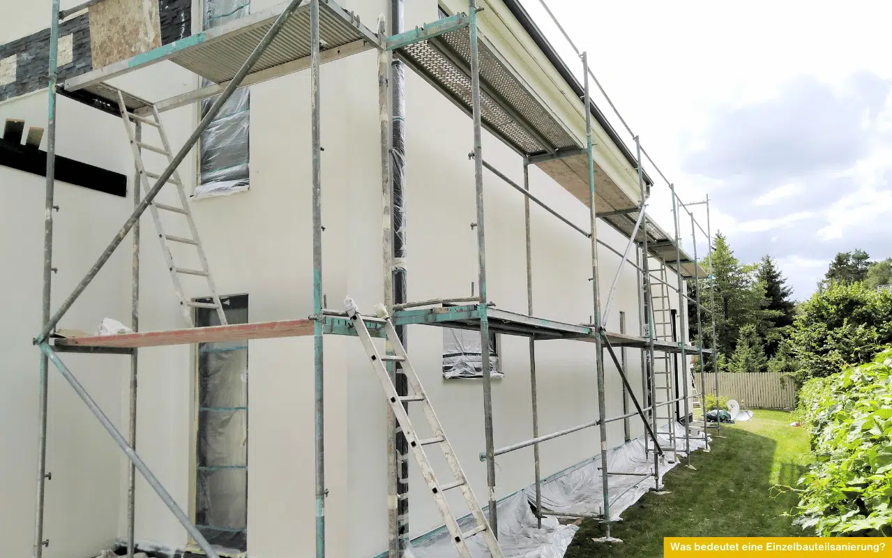 Das Bild zeigt ein Einfamilienhaus mit Baugerüst während einer Sanierung. Fenster und Wände sind abgedeckt, um einzelne Gebäudeteile – etwa Fassade oder Fenster – im Zuge einer Einzelbauteilsanierung zu modernisieren.