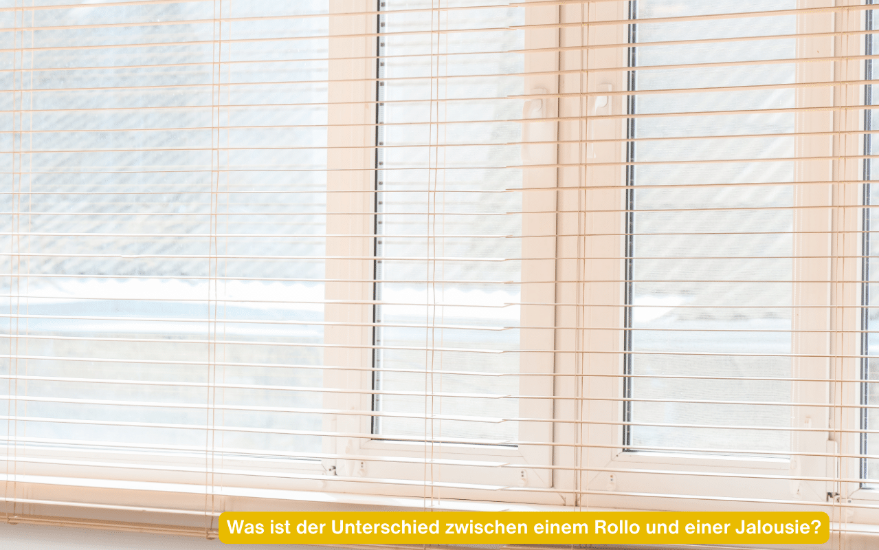 Was ist der Unterschied zwischen einem Rollo und einer Jalousie? Weiße Aluminium-Jalousie an einem hellen Fenster