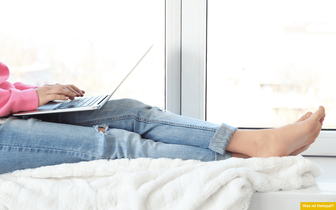 Was ist Helopal? Person sitzt entspannt mit Laptop auf einer weißen Fensterbank und arbeitet.