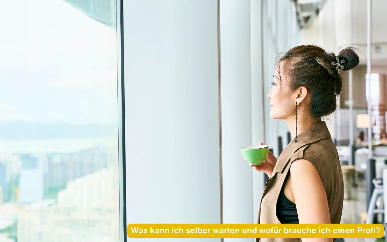 Was kann ich selber warten und wofür brauche ich einen Profi – Frau mit Tasse blickt nachdenklich aus einer großen Glasfront