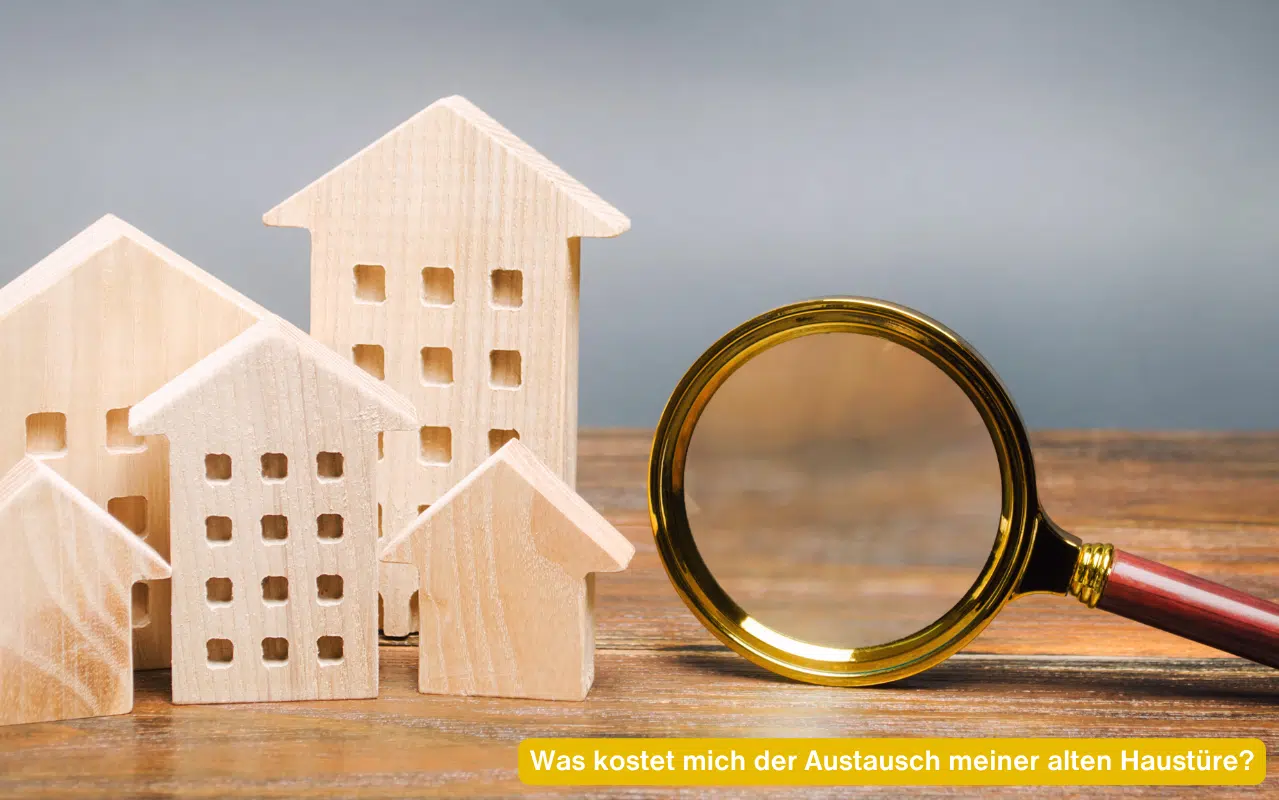 Was kostet mich der Austausch meiner alten Haustüre? Kleine Holzhäuser und eine Lupe liegen auf einer Tischoberfläche