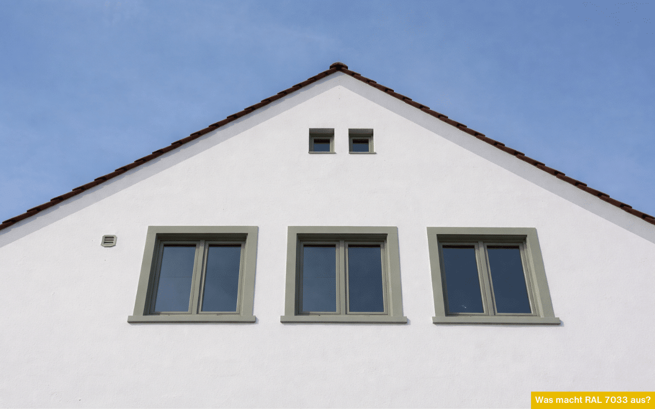 Was macht RAL 7033 aus? Hausfassade mit Fenstern in Zementgrau, ruhiger Grauton auf Weiß