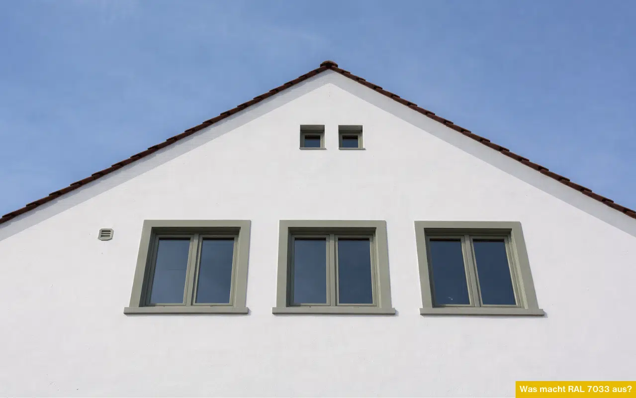 Was macht RAL 7033 aus? Hausfassade mit Fenstern in Zementgrau, ruhiger Grauton auf Weiß