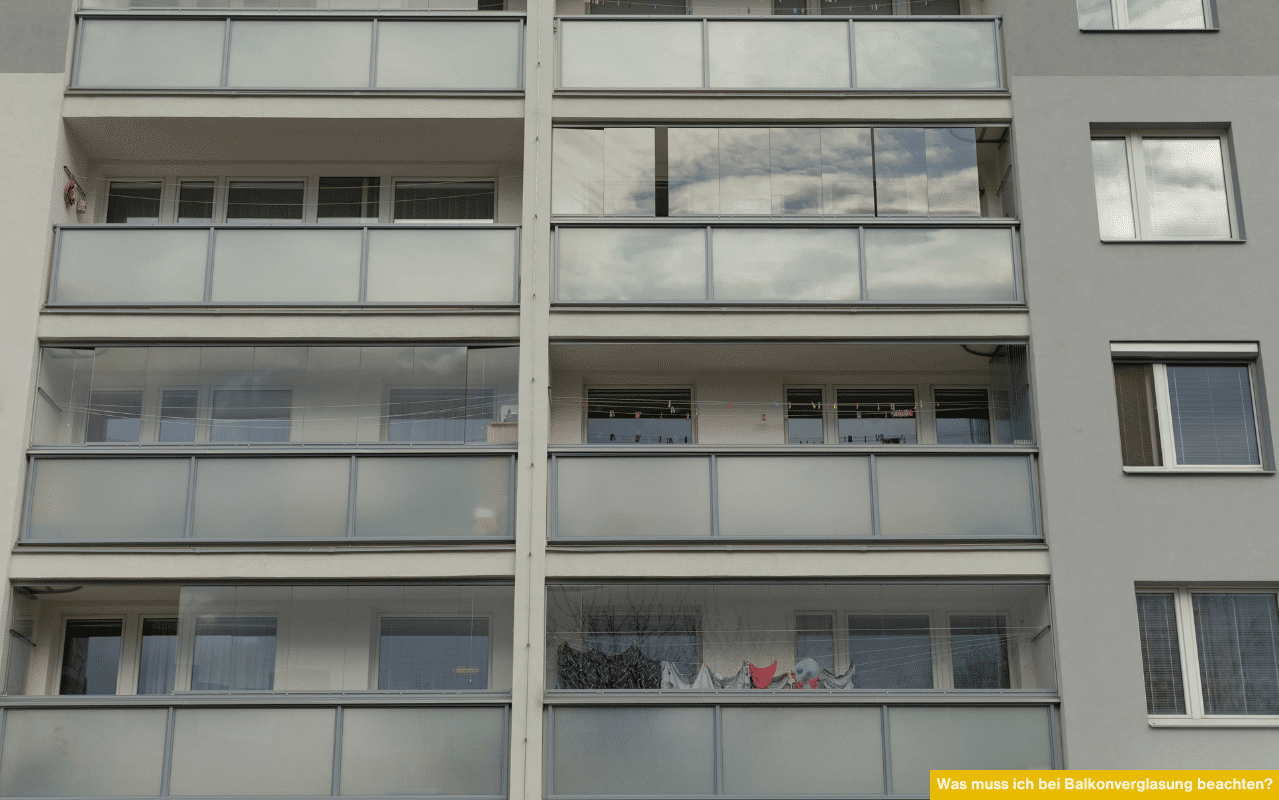 Was muss ich bei Balkonverglasung beachten? Mehrere verglaste Balkone an einer modernen Wohnhausfassade in Reihenanordnung.
