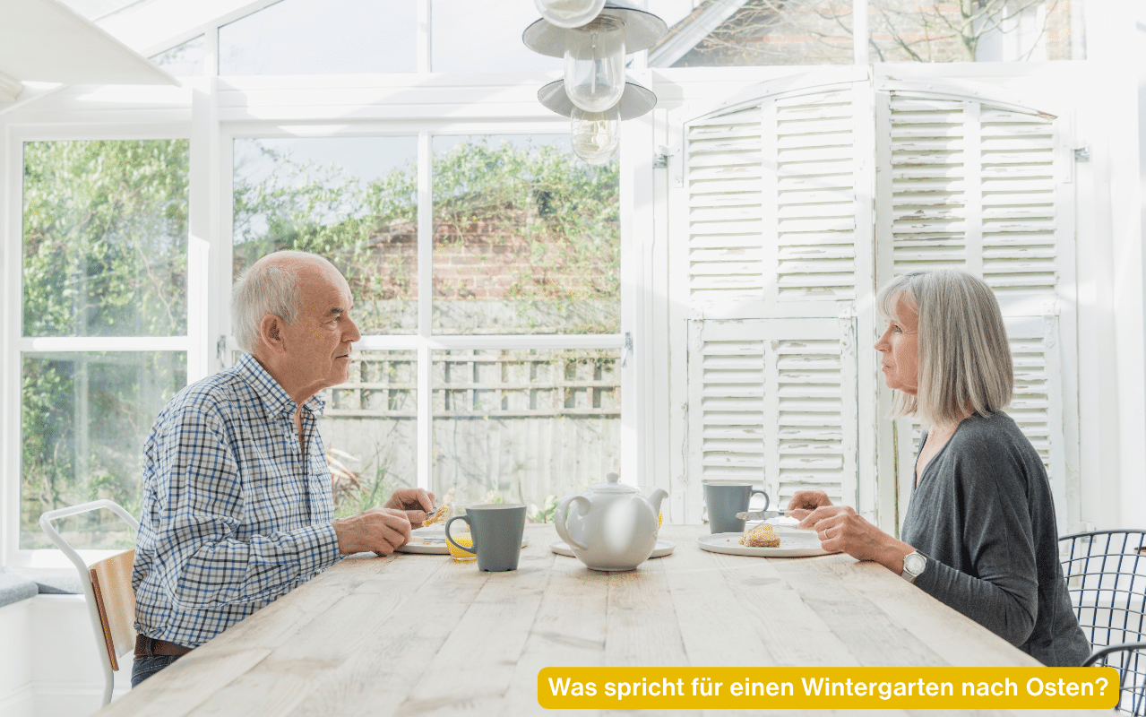 Was spricht für einen Wintergarten nach Osten? Älteres Paar beim Frühstück in einem hellen Wintergarten
