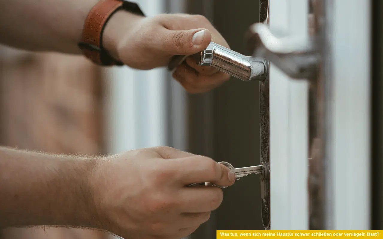 Was tun, wenn sich meine Haustür schwer schließen oder verriegeln lässt – Person versucht Haustür mit Schlüssel und Griff zu öffnen.