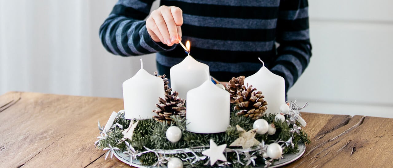 Ein liebevoll dekorierter Adventskranz mit weißen Kerzen und Tannenzweigen kündigt die Weihnachtszeit an. Das Motiv symbolisiert besinnliche Tage und den Betriebsurlaub von Fenster-Schmidinger zwischen Weihnachten und dem Jahreswechsel.