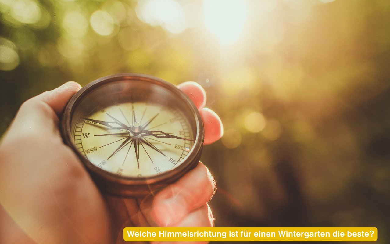 Welche Himmelsrichtung ist für einen Wintergarten die beste? Hand hält einen Kompass im Sonnenlicht