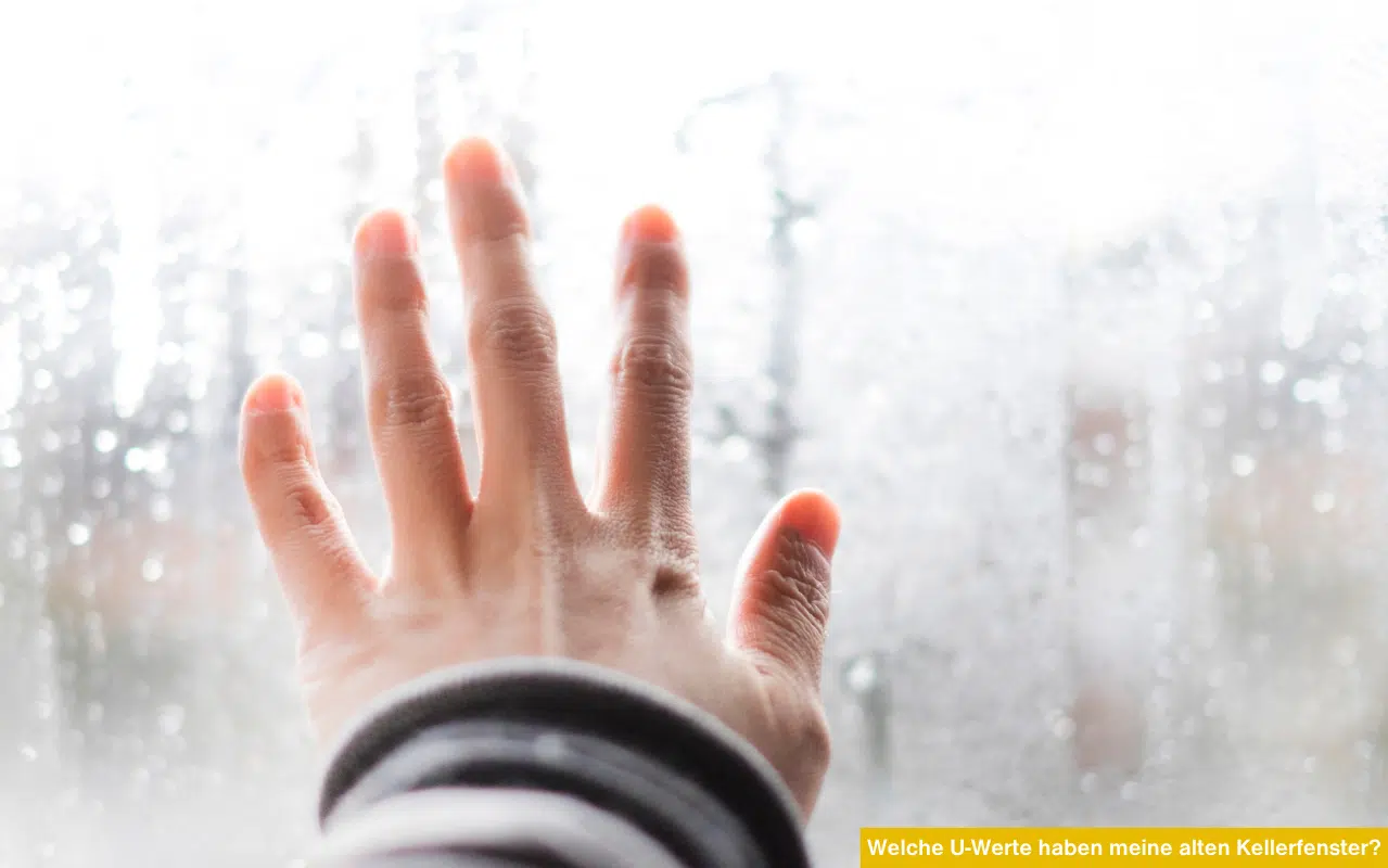 Welche U-Werte haben meine alten Kellerfenster? Hand auf einer beschlagenen Fensterscheibe symbolisiert Wärmeverlust.