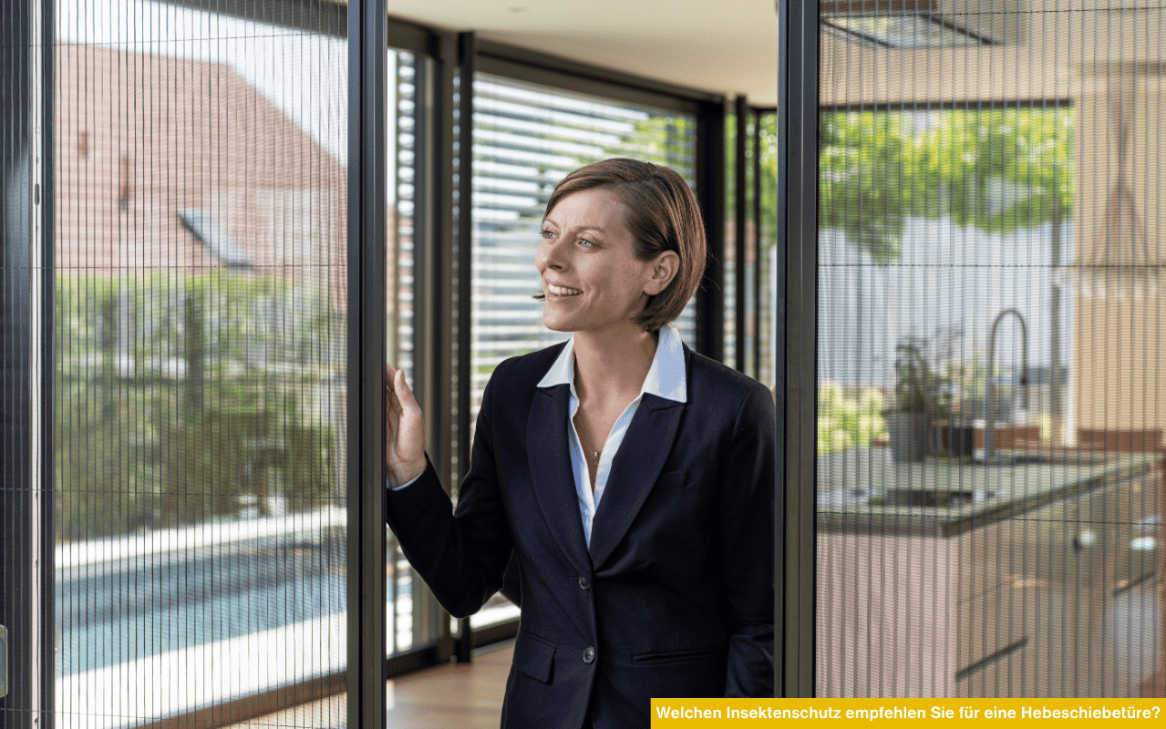 Eine Frau steht in einem modernen Wohnraum und schiebt ein feinmaschiges Insektenschutzgitter an einer Hebeschiebetür beiseite. Draußen ist ein Garten mit Pool zu sehen.