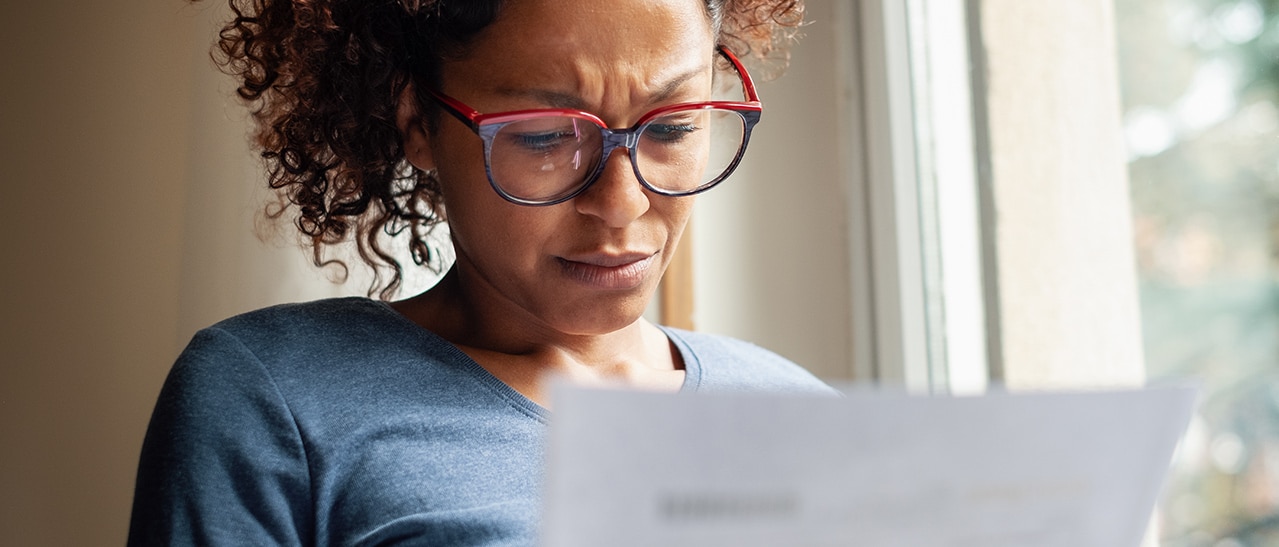 Nachdenkliche Frau schaut auf eine Rechnung am Fenster – thematisiert steigende Preise und die Frage: Werden Fenster im Jahr 2022 teurer?