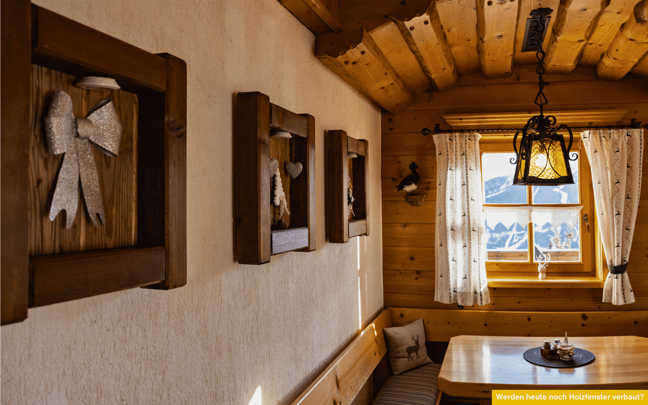 Werden heute noch Holzfenster verbaut? Traditionelle Holzfenster in rustikaler Almhütte mit gemütlicher Einrichtung und Blick in die Berge.