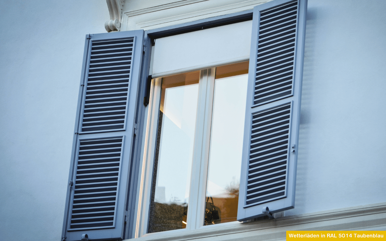 Wetterläden in RAL 5014 Taubenblau an einem weißen Fassadenfenster mit geöffneten Lamellenläden und reflektierender Glasscheibe