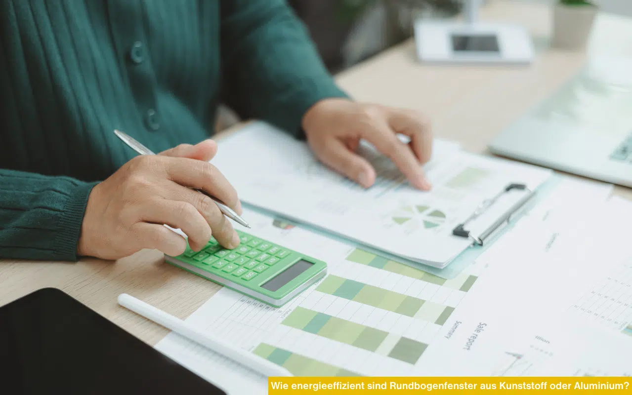 Wie energieeffizient sind Rundbogenfenster aus Kunststoff oder Aluminium? Hände bei der energetischen Berechnung am Schreibtisch.