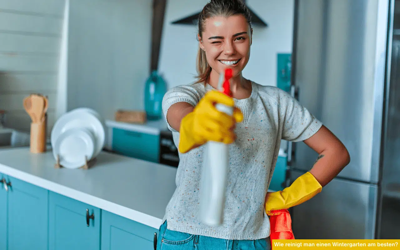 Wie reinigt man einen Wintergarten am besten? Frau mit Sprühflasche und Handschuhen zeigt Reinigung in Küche