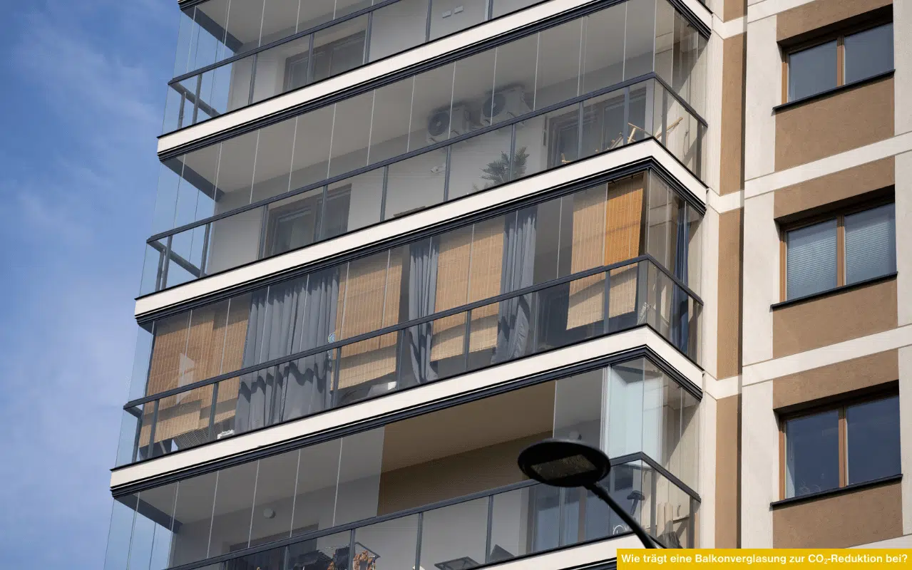 Hohe Wohnhausfassade mit durchgehender Balkonverglasung, die die Wohnungen optisch schützt und solare Wärmegewinne ermöglicht.