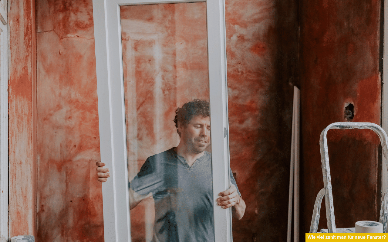 Wie viel zahlt man für neue Fenster? Handwerker trägt neues Fenster in Baustelle mit unverputzter Wand und Renovierungsbedarf.