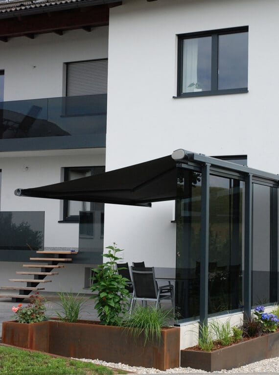 Es geht um eine Windschutz-Idee für die Terrasse, umgesetzt mit Glas und einer Beschattung. Ziel ist mehr Komfort draußen, weniger Wind und bei Bedarf auch Schatten, ohne dass es optisch schwer wirkt.