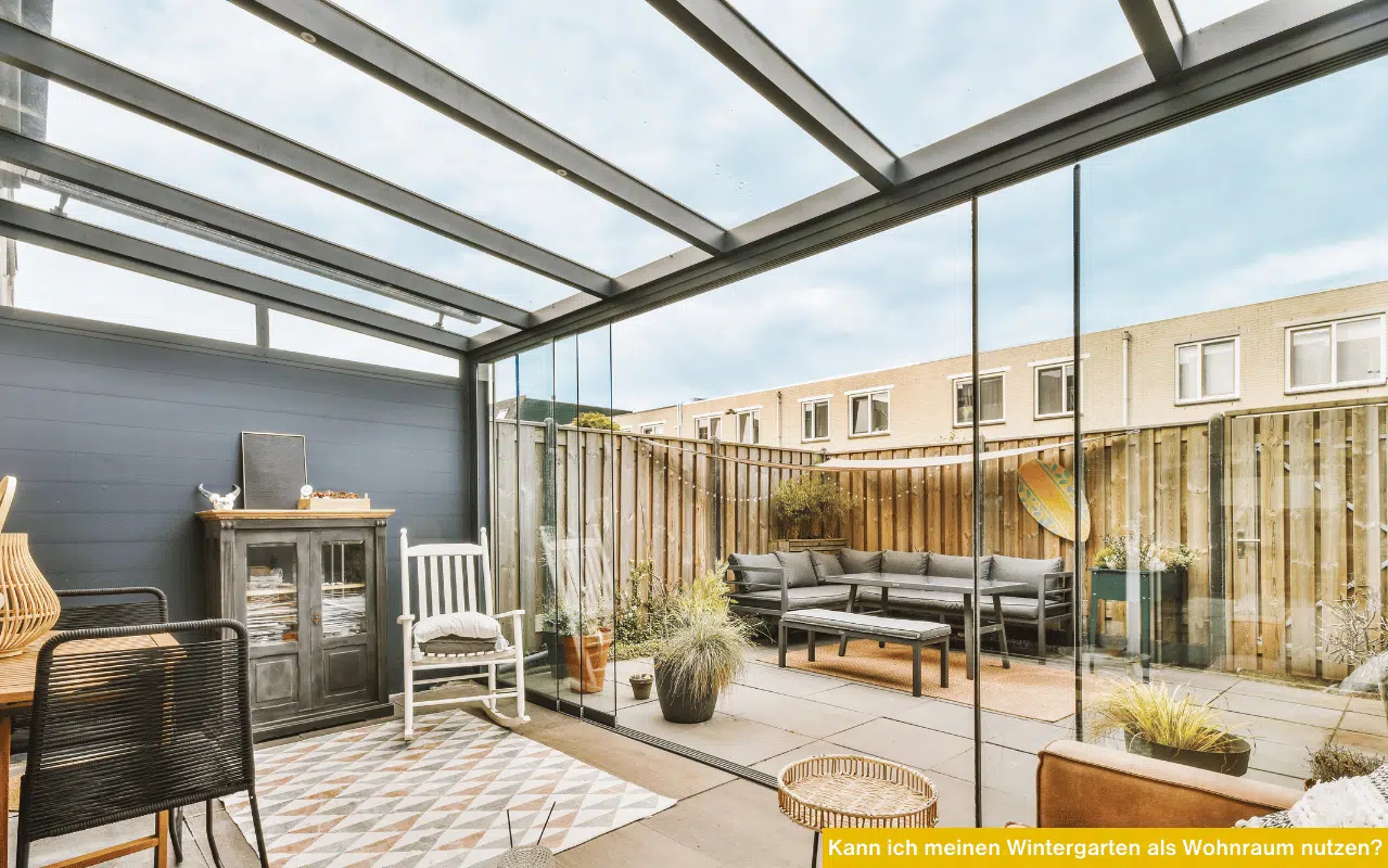 Moderner Wintergarten mit Glasdach, Glasschiebewänden und gemütlicher Einrichtung, der nahtlos in eine Terrasse übergeht.