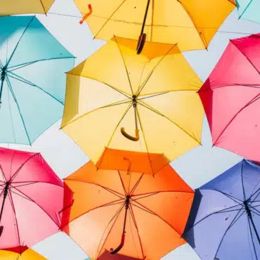 Wintergarten-Beschattung Symbolbild mit vielen bunten Regenschirmen vor hellem Himmel