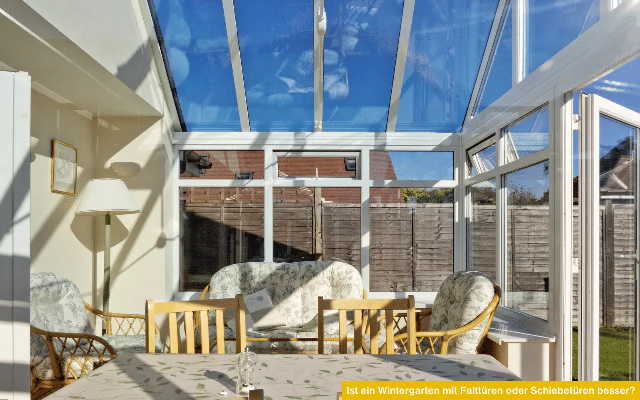 Heller Wintergarten-Innenraum mit weißem Rahmen, Glasdach, Blumenmuster-Sofas und Blick auf einen Holzzaun.