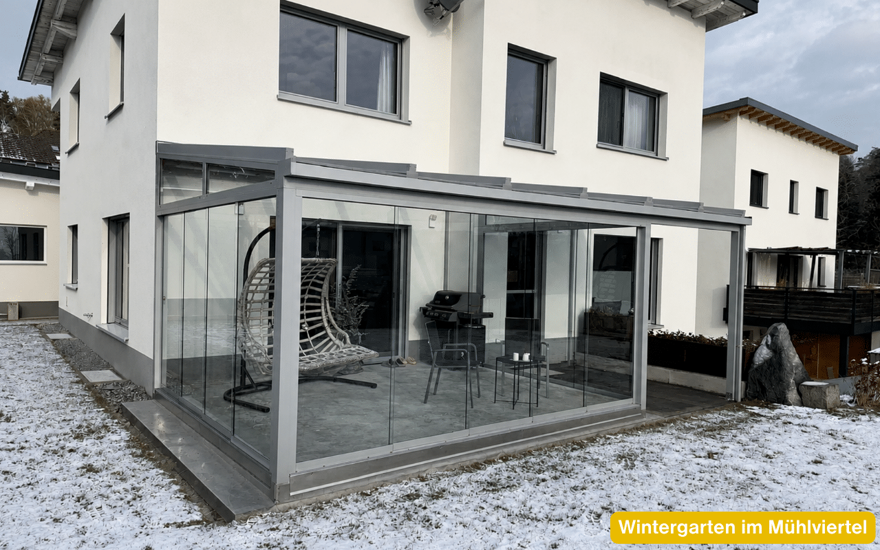 Wintergarten in Freistadt als verglaster Anbau mit Terrasse, Hängesessel und Sitzplatz bei Schnee im Garten