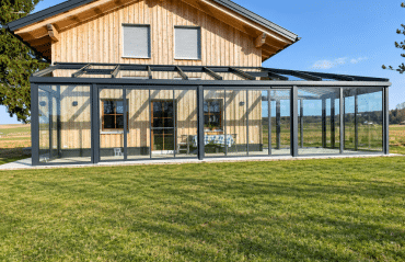 Wintergarten in Gmunden mit schwarzer Aluminiumkonstruktion und großen Glasflächen an einem Holzhaus