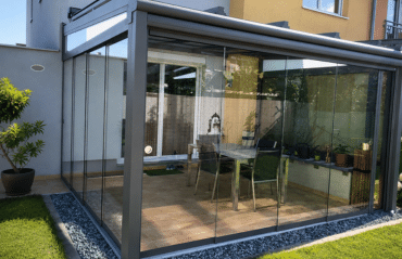 Wintergarten in Wels mit grauem Aluminiumrahmen und rahmenlosen Glasschiebeelementen im Garten