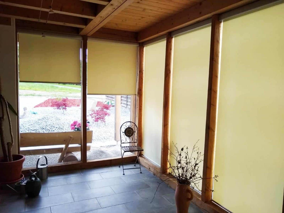 Wintergarten mit Holzkonstruktion und hellen Innenrollos vor den Glaselementen