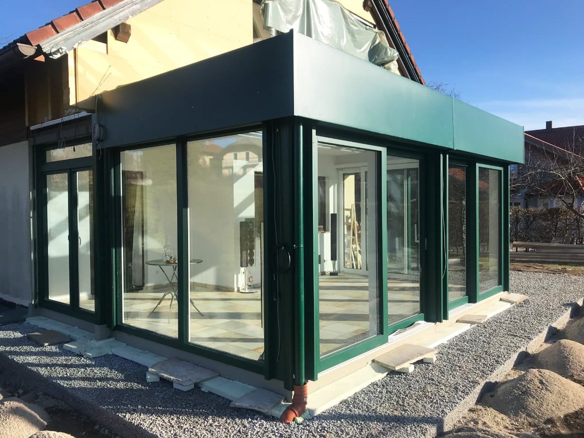 Aluminium-Wintergarten mit Flachdachoptik in Moosgrün an einem Einfamilienhaus in Mondsee im Bezirk Vöcklabruck