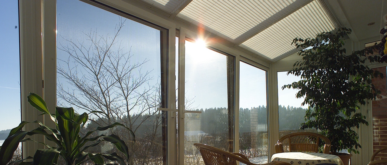 Wintergarten Plissees am Glasdach als Sonnenschutz mit Blick in eine winterliche Landschaft