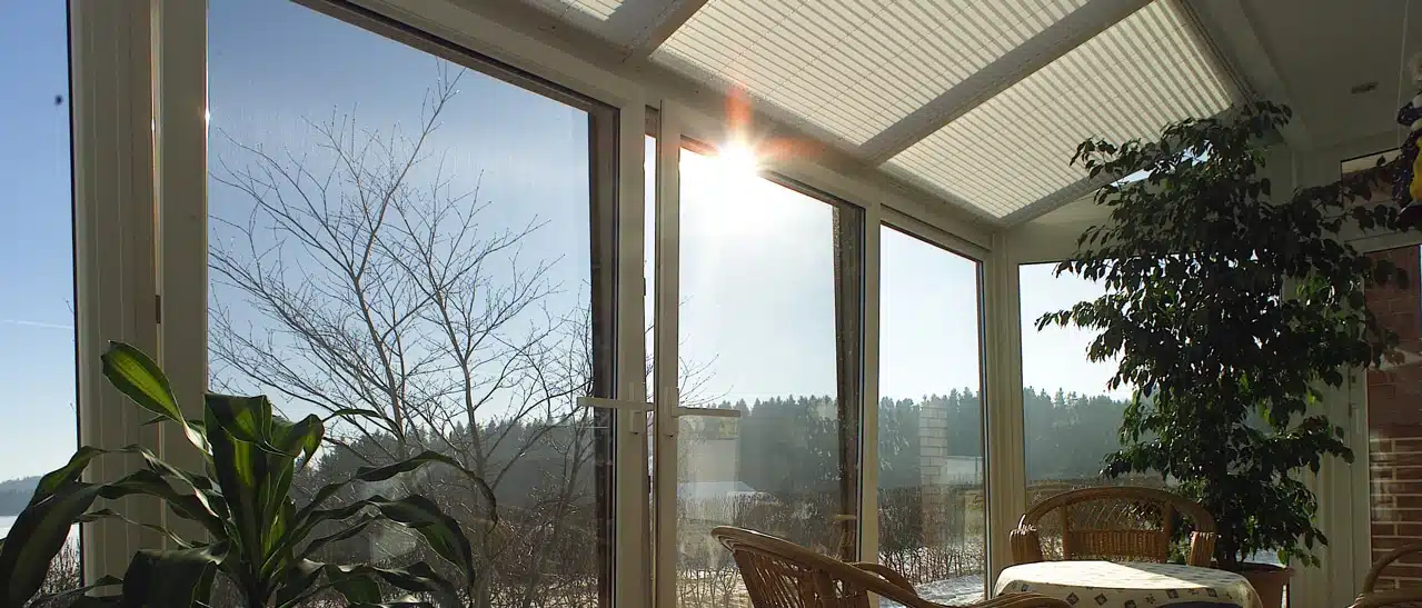 Wintergarten Plissees am Glasdach als Sonnenschutz mit Blick in eine winterliche Landschaft