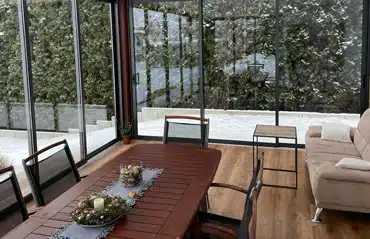 Gemütlicher verglaster Wintergarten mit Essbereich und Sofa im Schnee zeigt Inspiration für eine Wintergartenfirma in Ihrer Nähe.
