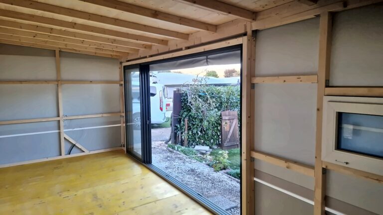 Geöffnetes Schiebeelement im Wohnwagen-Anbau mit Blick in den Garten